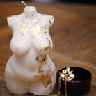 Bougie artisanale représentant une grande femme aux formes généreuses, ornée de feuilles d'or qui subliment ses courbes élégantes. Une pièce décorative raffinée, idéale pour instaurer une ambiance chaleureuse et sophistiquée dans tout intérieur.