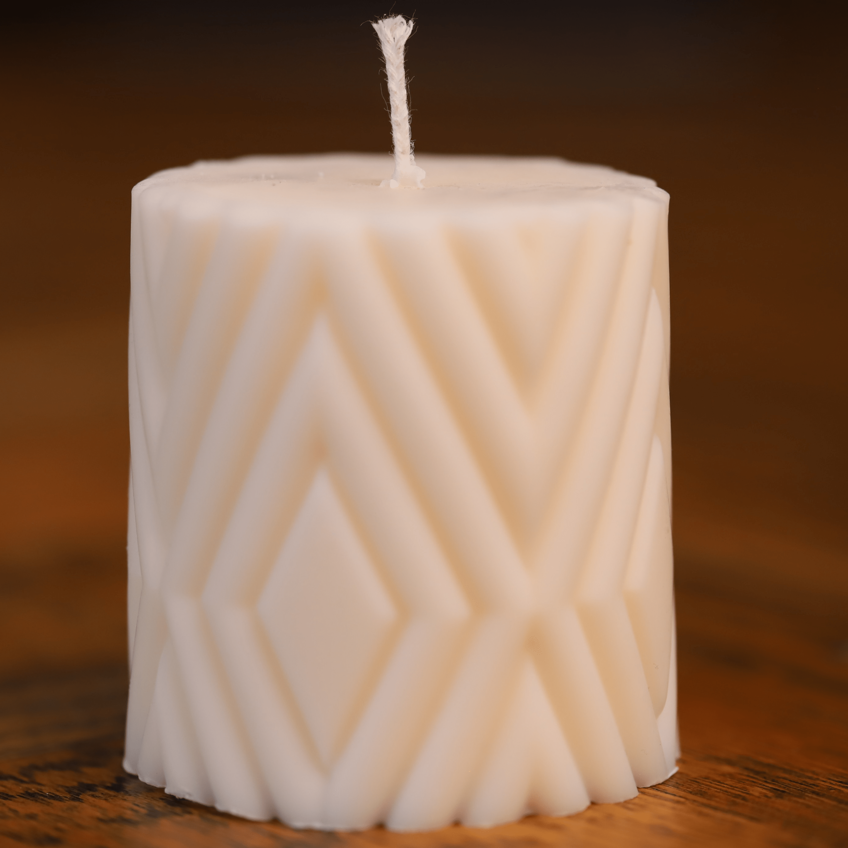 Bougie artisanale en cire naturelle avec un motif géométrique en relief, ajoutant une touche élégante et moderne à la décoration intérieure.