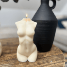Bougie en forme de buste féminin allumée, diffusant une lumière douce et apaisante. Son design épuré et raffiné crée une ambiance intime et élégante, parfaite pour sublimer un espace de vie avec délicatesse.
