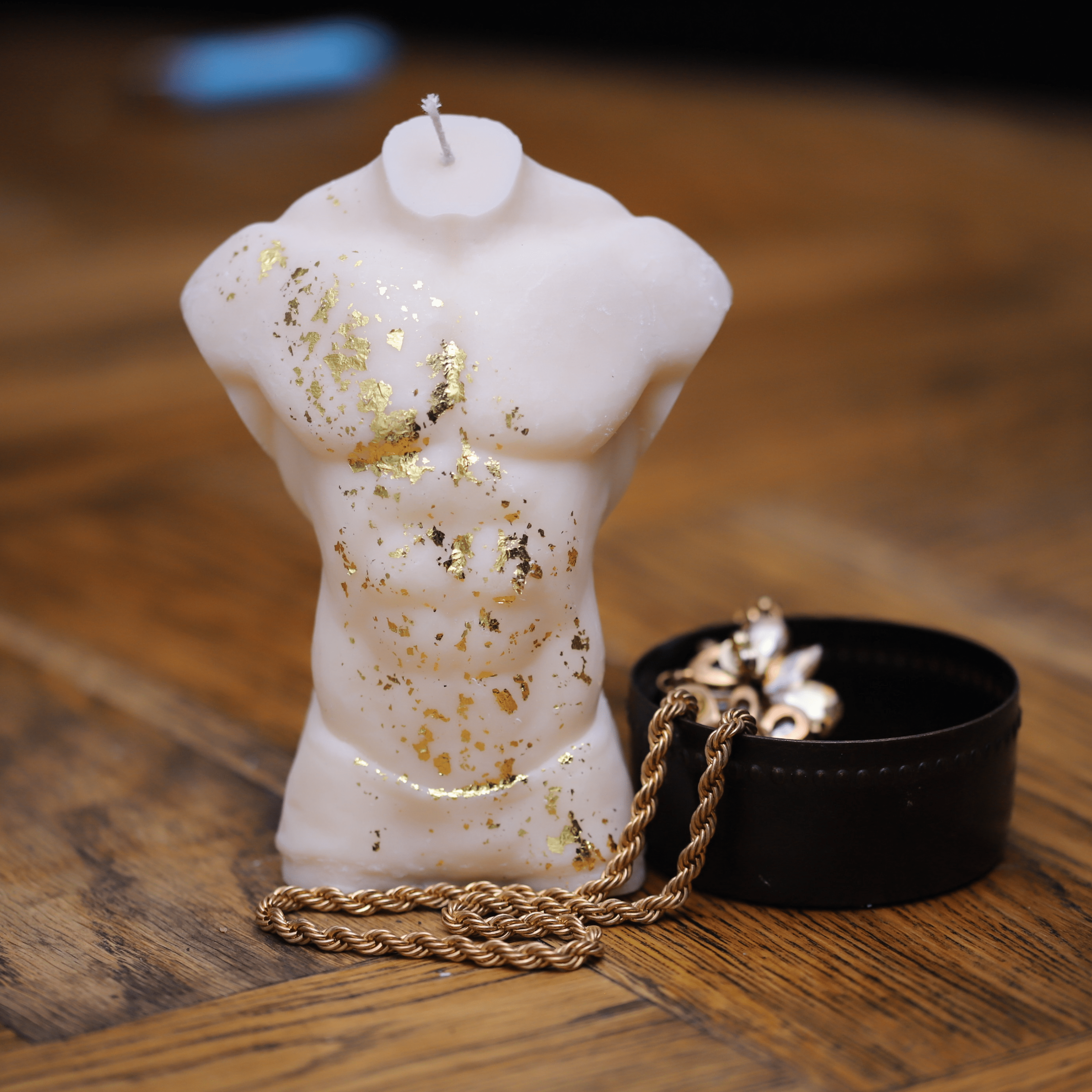 Bougie artisanale en forme de buste masculin sculpté avec finesse et rehaussé de délicates touches de feuilles d'or. Son design raffiné et puissant évoque la force et l'élégance, en faisant un élément de décoration idéal pour une ambiance sophistiquée et intemporelle.