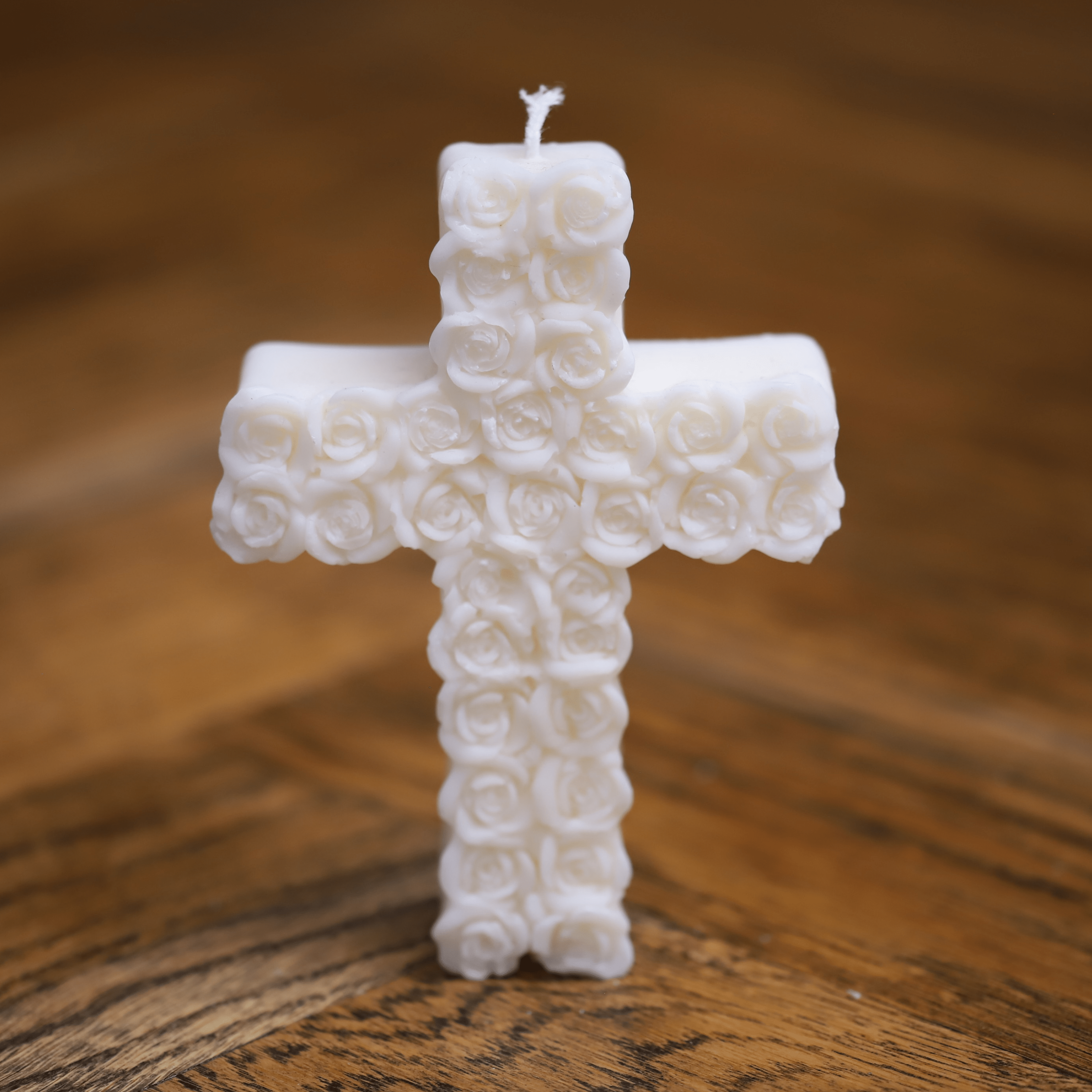 Bougie artisanale en forme de croix avec motif de roses, idéale pour une décoration religieuse et spirituelle.