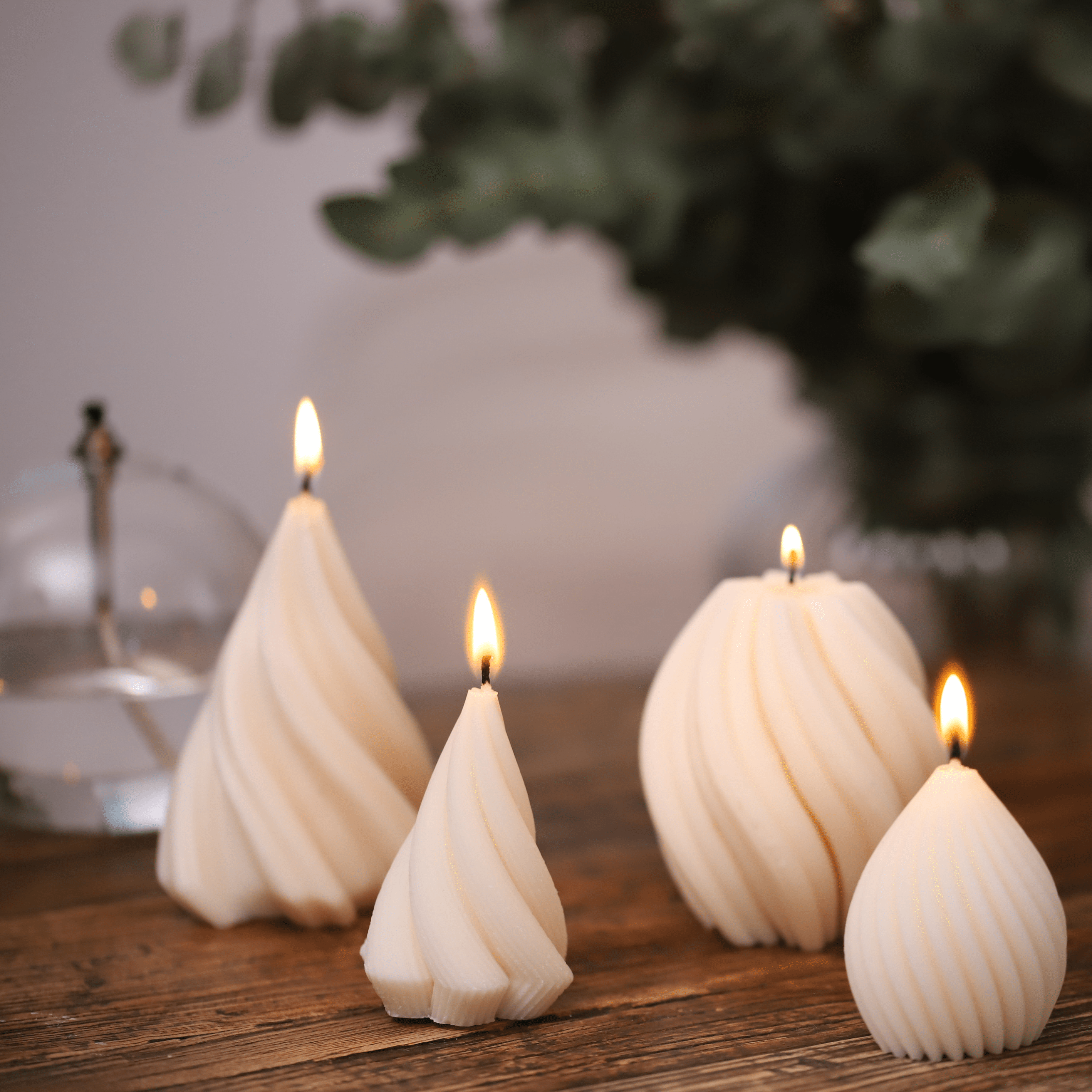 Ensemble de bougies torsadées en cire blanche, de différentes formes et tailles, allumées sur une table en bois, créant une ambiance conviviale. 
Fabriquées artisanalement en Alsace.
