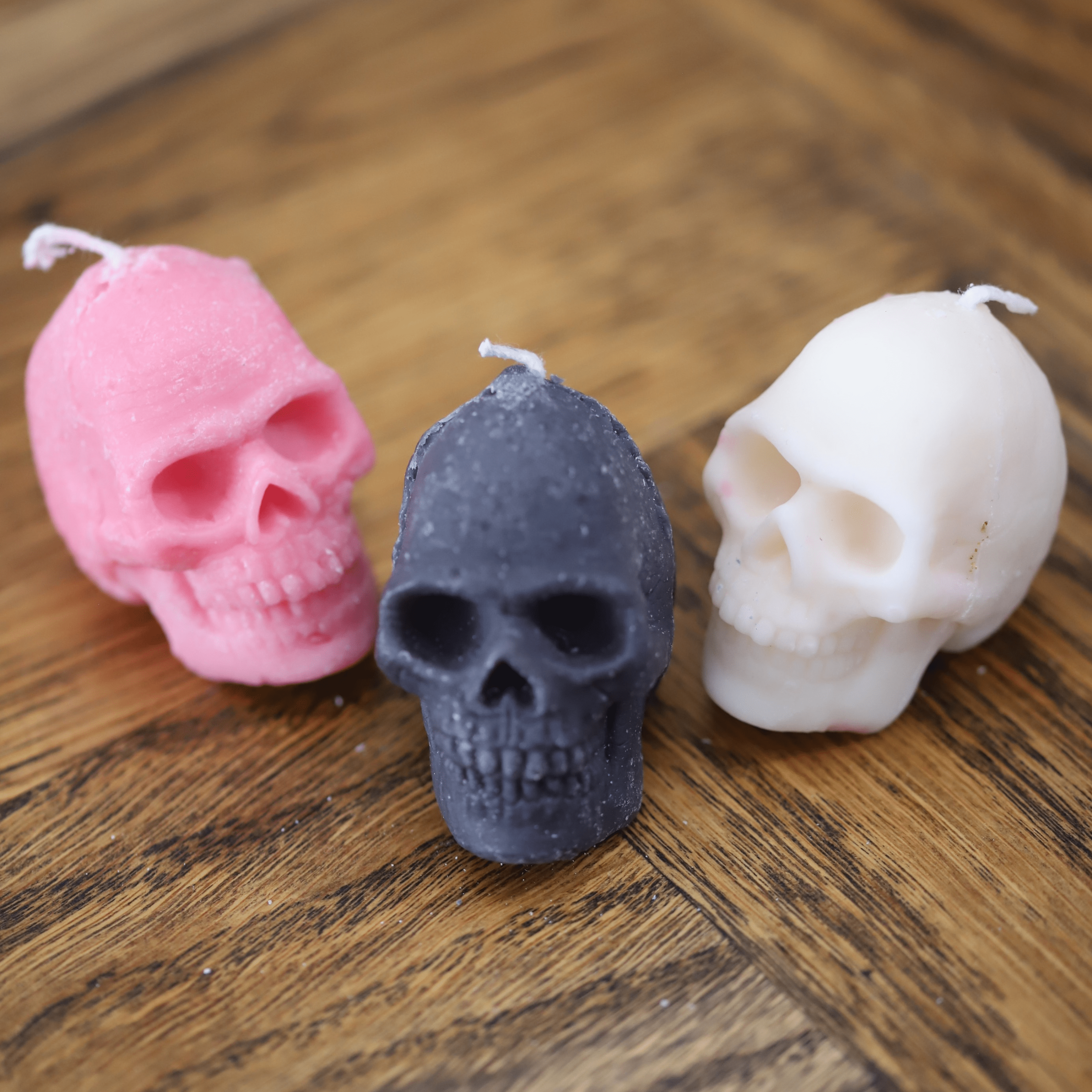 Bougies artisanales en forme de crâne, disponibles en noir, rose et blanc, parfaites pour une décoration originale et audacieuse, idéales pour Halloween ou une ambiance gothique.
