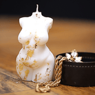 Bougie artisanale en forme de buste féminin miniature, sublimée par de délicates feuilles d'or qui soulignent avec élégance les courbes généreuses du corps. Véritable pièce décorative, cette bougie apporte une touche raffinée et sophistiquée à tout intérieur, et constitue un cadeau original et distingué.