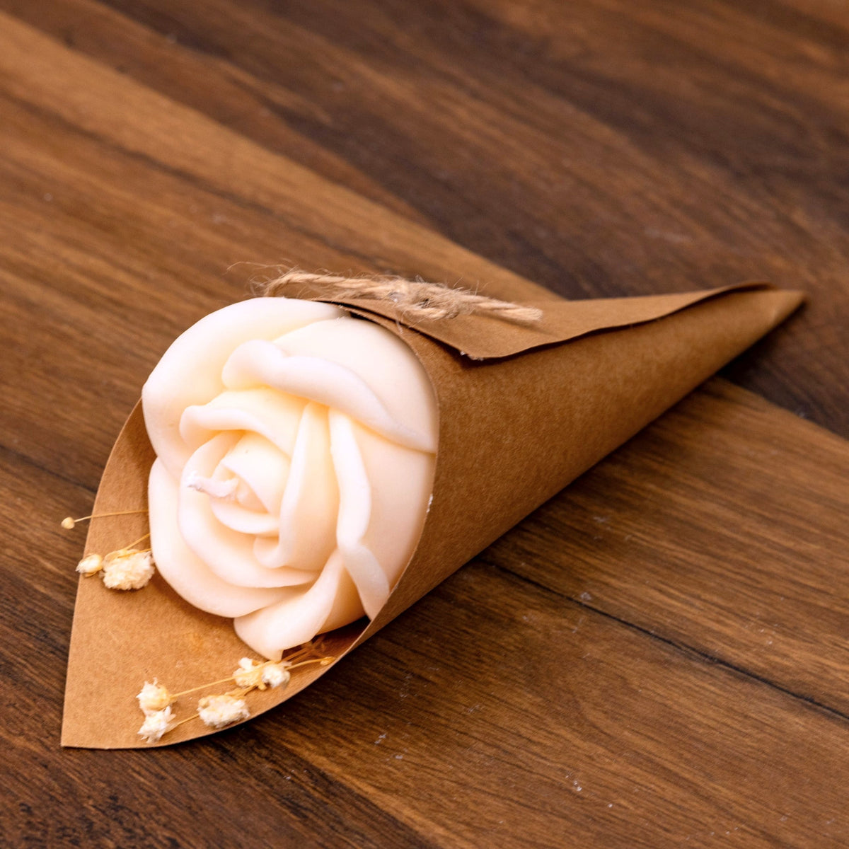 Bougie rose blanche dans un cornet kraft avec gypsophile