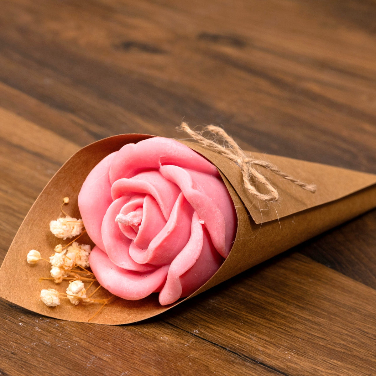 Bougie rose rose dans un cornet kraft avec gypsophile