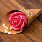 Bougie rose rouge dans un cornet kraft avec gypsophile