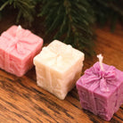 Bougies petit cadeau de Noël rose, blanche et violette en forme de paquet cadeau